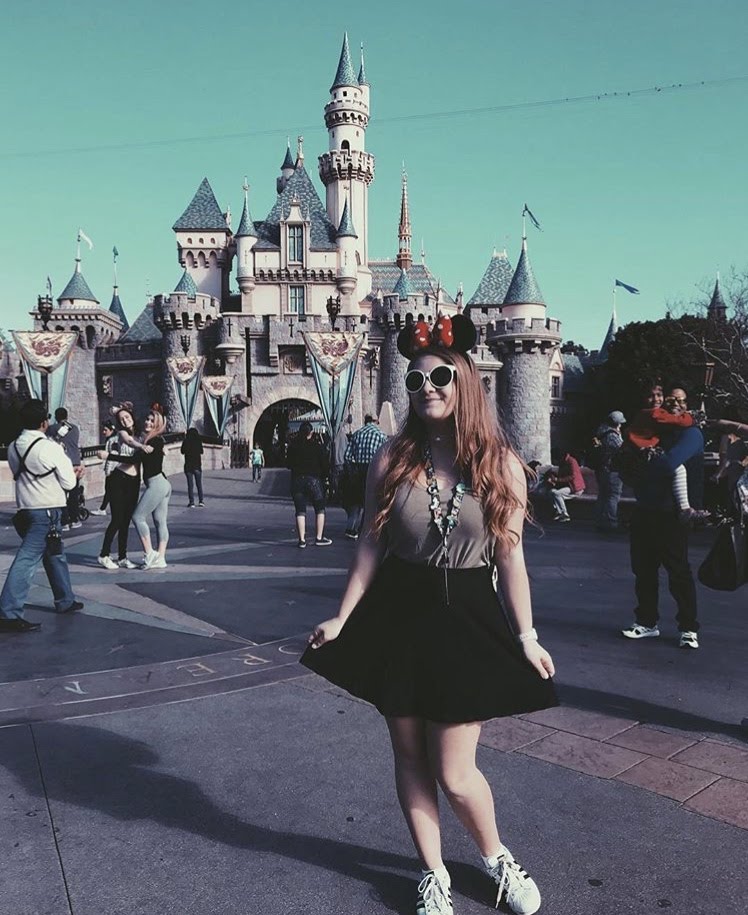 A teenage girl posing in front of Cinderella's Castle in Disneyland